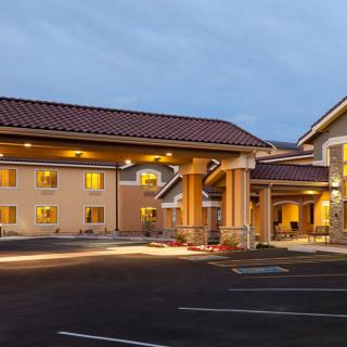 A well-lit hotel exterior with a parking lot at dusk.