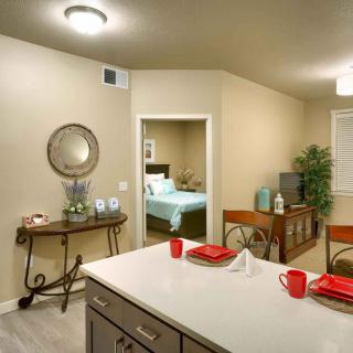 Modern dining area with a view into the bedroom, featuring clean decor and red accents.