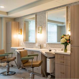 A modern salon interior with stylish chairs and mirrors, complemented by warm lighting and a bouquet of flowers.
