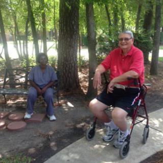 Two people enjoying a relaxing day in the park, with one seated on a walker and the other on a bench.