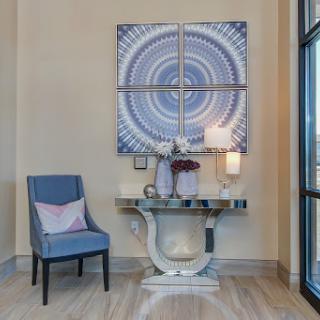 A stylish corner featuring modern decor with a geometric artwork, elegant chair, and a decorative console table.