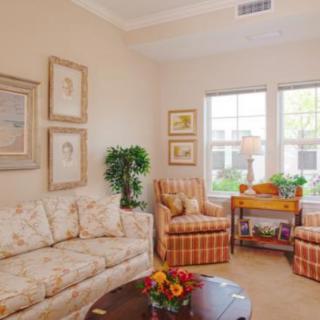 A cozy living room with a floral sofa, striped armchairs, and decorative artwork on the walls.