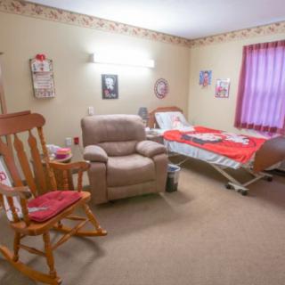 A cozy room in a nursing home with a hospital bed, comfortable armchair, and rocking chair.