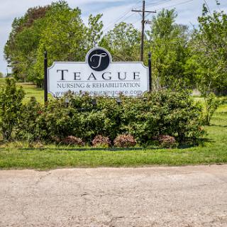 A sign marking the entrance to Teague, surrounded by lush greenery.