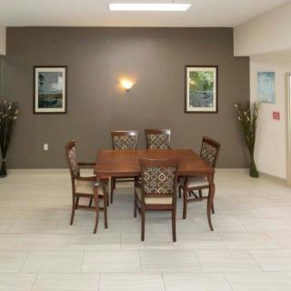 A neatly arranged dining room with a wooden table, six chairs, artwork on the walls, and ambient lighting.
