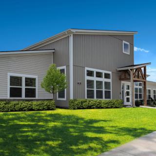 A modern residential building with a well-maintained lawn on a sunny day.