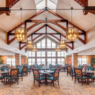 A spacious dining area with elegant chandeliers and wooden beam architecture.