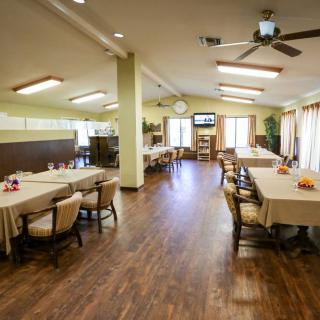 A spacious and well-lit dining area with wooden floors, tables, and chairs.