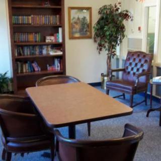A cozy office conference room with a table, chairs, and a bookshelf.