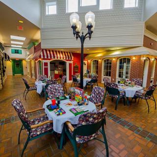 A cozy indoor dining area with tables and chairs, featuring decorative elements and a central lamppost.