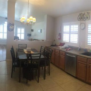 A bright kitchen and dining area with a table, chairs, and a chandelier.