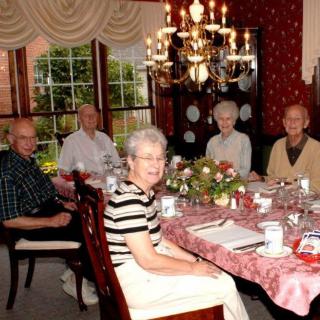 A group of seniors enjoying a meal together at a beautifully set dining table.