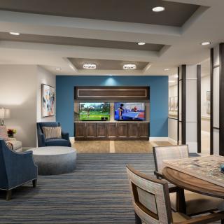 A modern living room with comfortable seating and dual televisions on a blue accent wall.