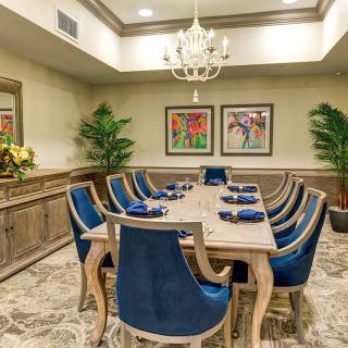 Elegant dining room with a large table, blue chairs, and a chandelier.