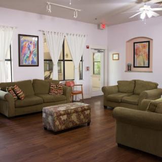 A cozy living room featuring green sofas, artistic wall decor, and natural light.