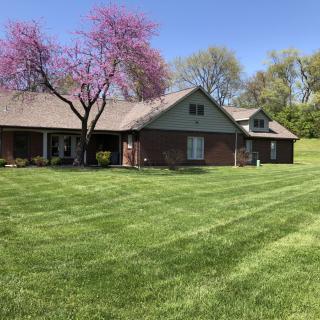 A suburban house with a well-maintained lawn and blooming trees during spring.
