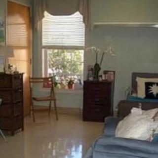 A cozy bedroom with a window, dresser, chair, and couch.
