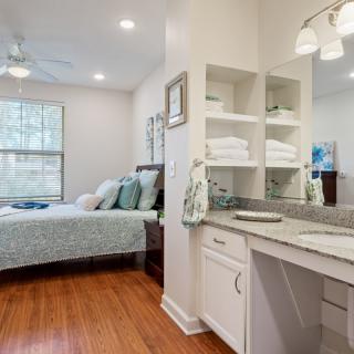 A modern bedroom with a comfortable bed and a well-organized vanity area.