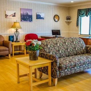 A cozy living room setting featuring a patterned sofa, wooden furniture, and decorative elements.