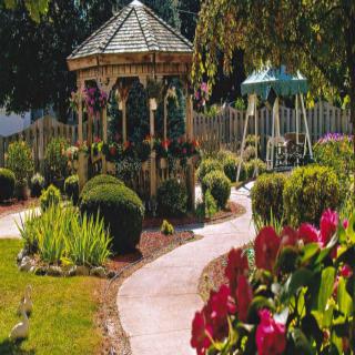 A beautifully landscaped garden featuring a gazebo and winding pathway surrounded by flowers and shrubs.