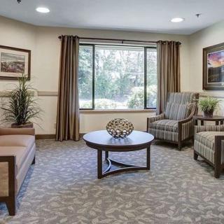A cozy living room with comfortable seating and a large window, featuring neutral tones and modern decor.