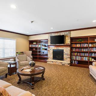 A cozy living room featuring comfortable seating, a modern fireplace, and built-in bookshelves filled with books.