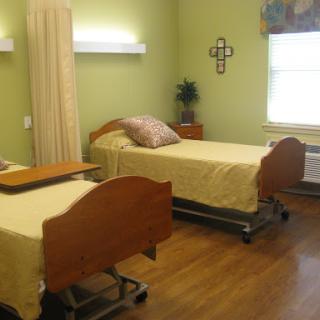 A well-lit hospital room featuring two adjustable patient beds with yellow bedding.