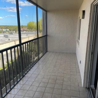 A spacious screened-in balcony with tiled flooring and a scenic view.