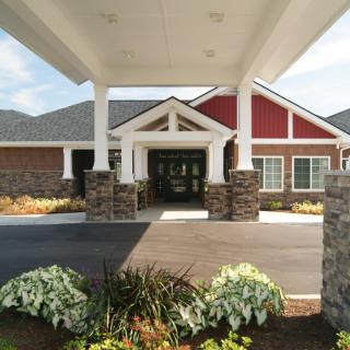 Front entrance of a modern building with stone columns and landscaped surroundings.