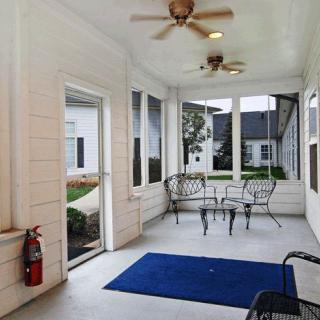 A cozy porch area with seating, ceiling fans, and windows overlooking the outside.