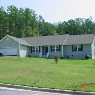 A charming single-story house with a well-maintained front yard surrounded by trees.