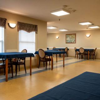 An empty dining area with tables and chairs arranged neatly, featuring warm lighting and decor.