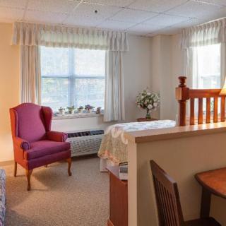 A cozy bedroom with a comfortable chair and a well-lit window.