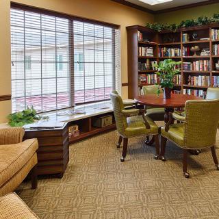 A cozy library reading room with bookshelves, a table, and comfortable seating.