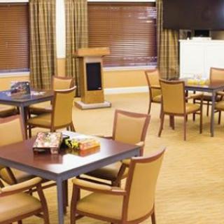 An empty conference room set up with tables and chairs, featuring a podium and television.