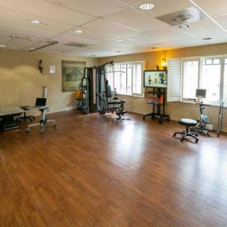 A spacious gym area with exercise equipment and wooden flooring.