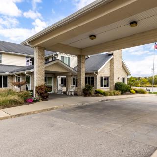 The exterior of a building with a covered driveway and surrounding greenery.