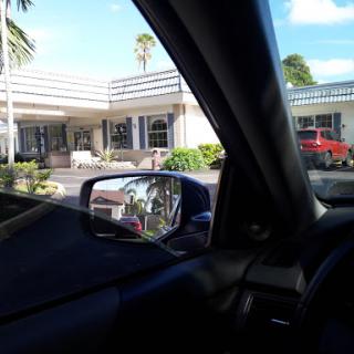 View from inside a car showing a building and reflection in the side mirror.