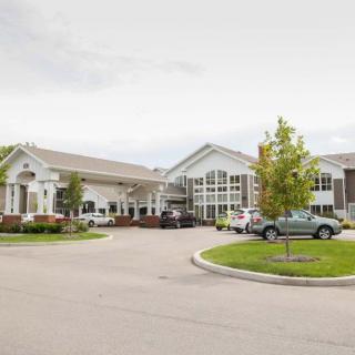A modern building with a landscaped parking area and several parked cars.