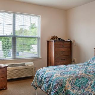 A cozy bedroom with a large window and patterned bedspread.