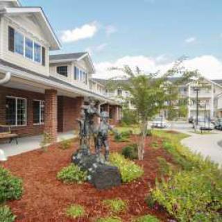 A suburban residential building with a landscaped garden and statue in the foreground.