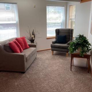 A cozy living room with a sofa, armchair, and indoor plants.