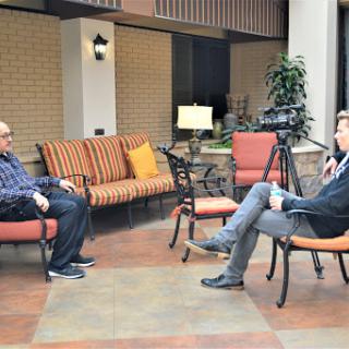 Two individuals engaged in an interview in a cozy indoor seating area.
