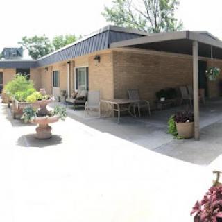 A sunny outdoor view of a residential building with landscaped patio and flower pots.