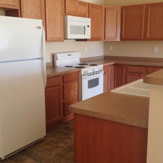 A modern kitchen with wooden cabinets, a refrigerator, microwave, oven, and ample countertop space.