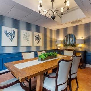 A modern dining room with a wooden table, elegant chairs, and decorative artwork on the walls.