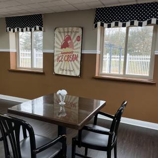A cozy dining area with a table and chairs, featuring artwork and polka dot curtains.