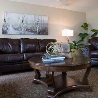 A cozy living room featuring dark leather sofas, a wooden coffee table, and modern decor.