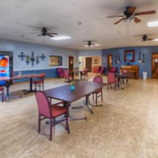 A spacious dining area with tables and chairs, decorated with wall art and equipped with ceiling fans.