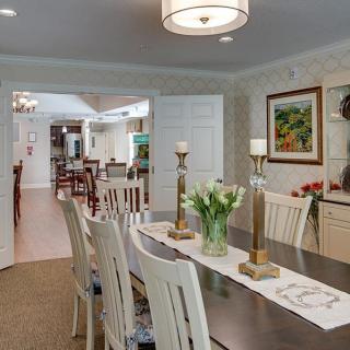 A well-decorated dining room with a long table, chairs, and elegant lighting.